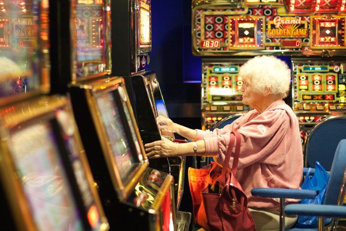 After a few bingo games, an elderly woman tries her luck on a fruit machine