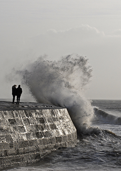 Stormy wave on The Cobb with couple, Lyme Regis, Dorset
