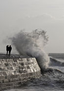 Stormy wave on The Cobb with couple, Lyme Regis, Dorset